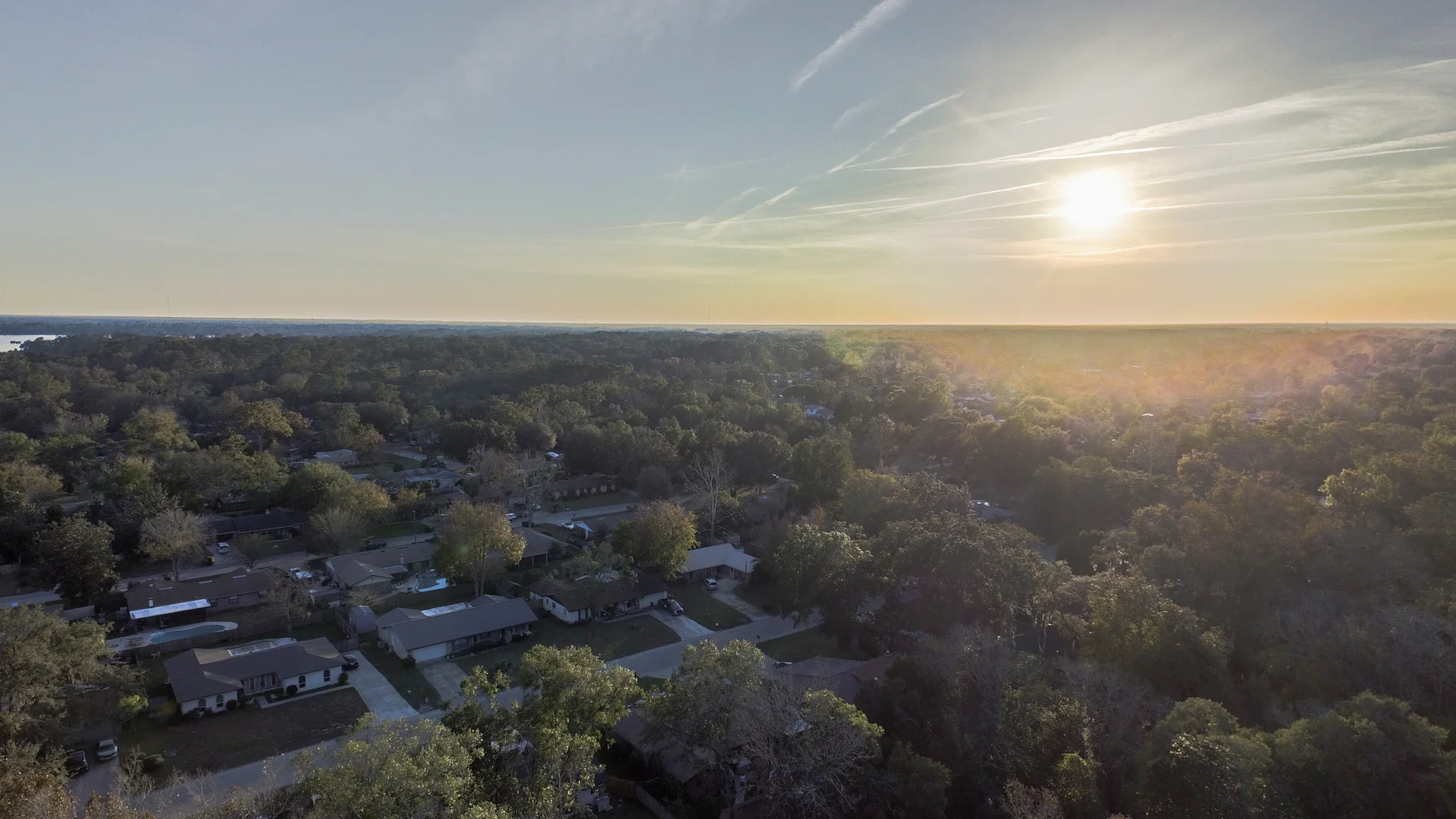 Warm evening light over trees and neighborhood rooftops.