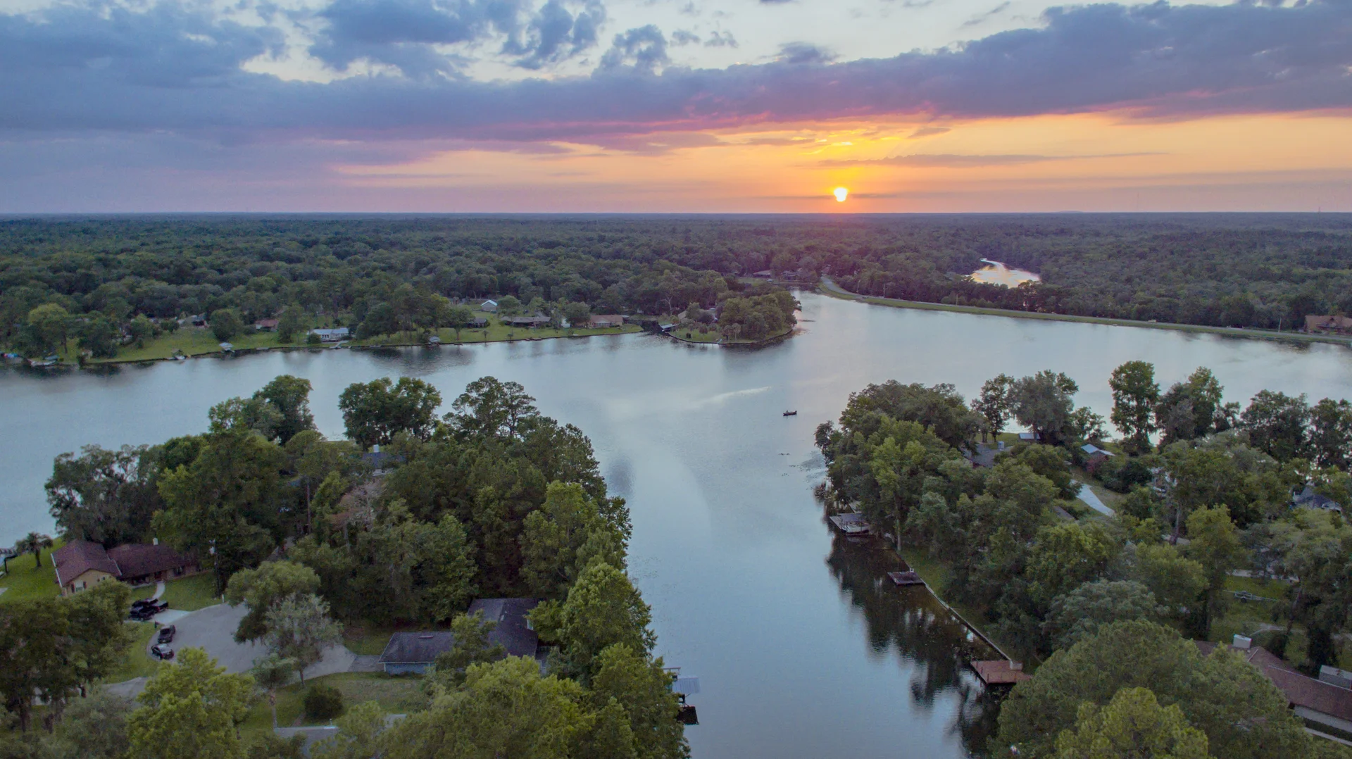 Sunset over the tree-lined waterways of Lake Asbury.